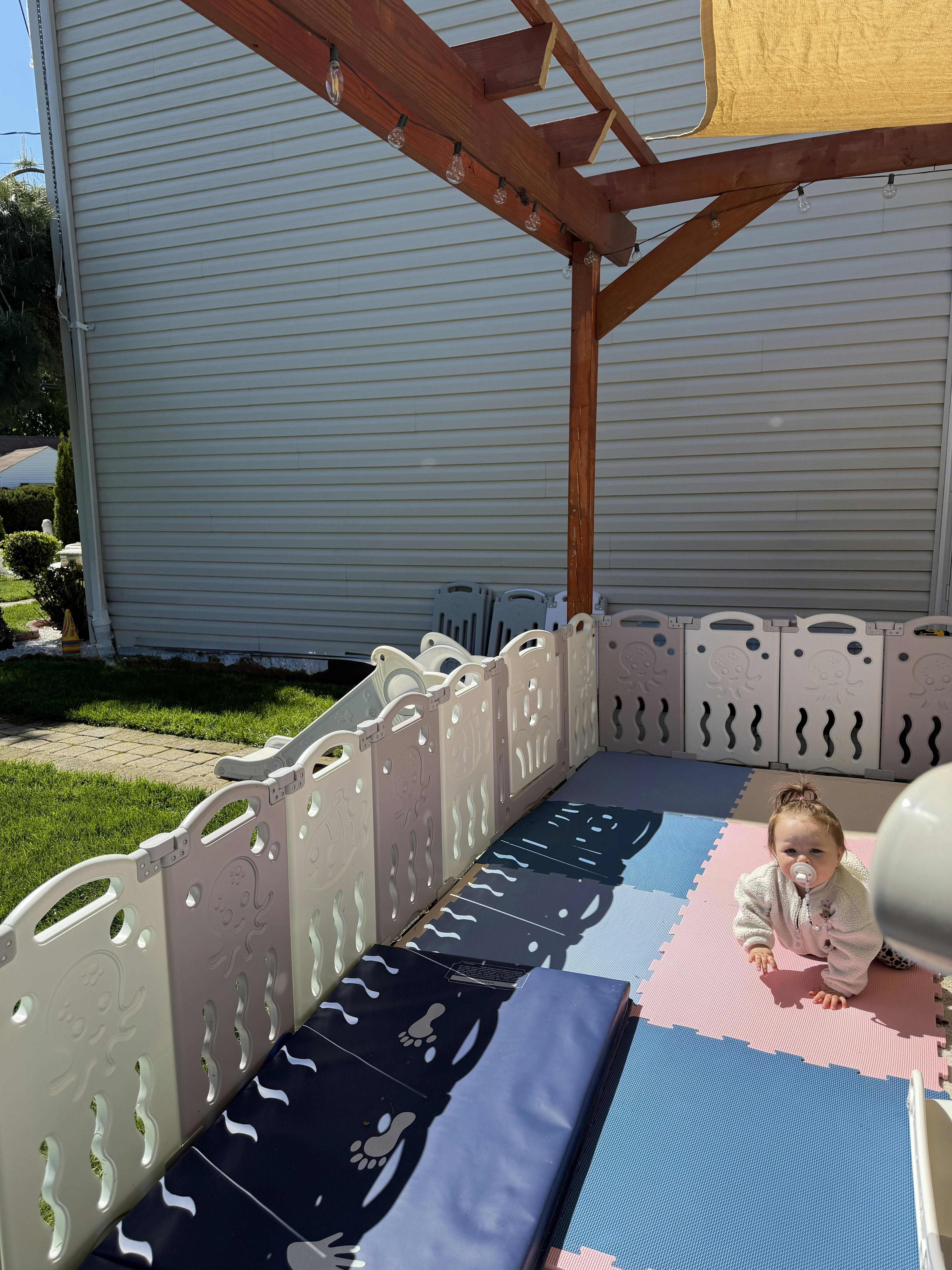 Child crawling on a play mat inside a playpen