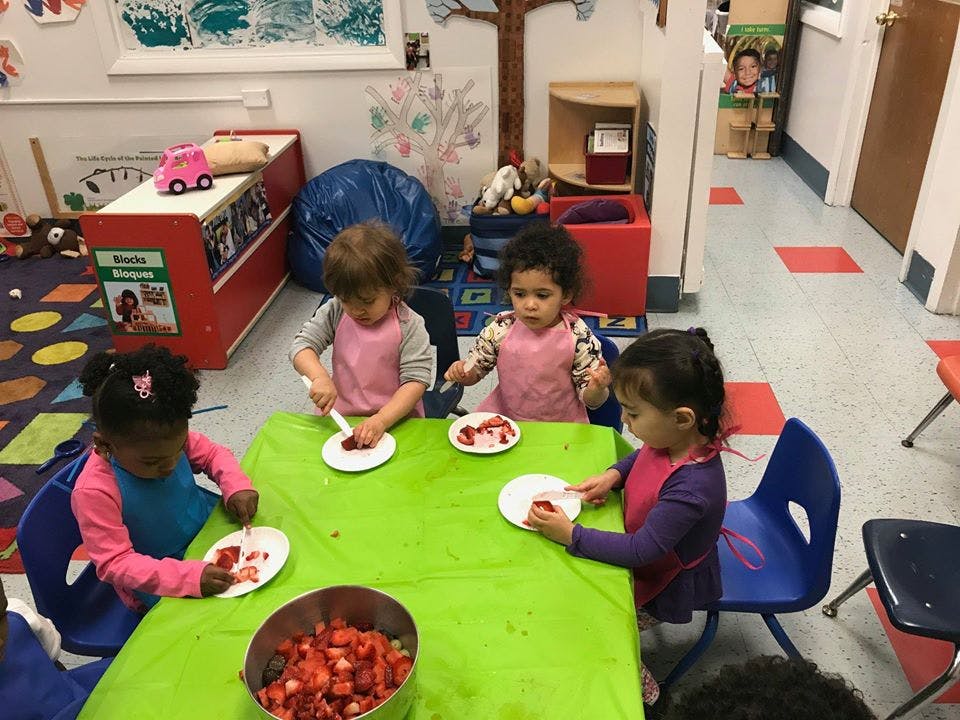 Children at a table with plates and a bowl of strawberries