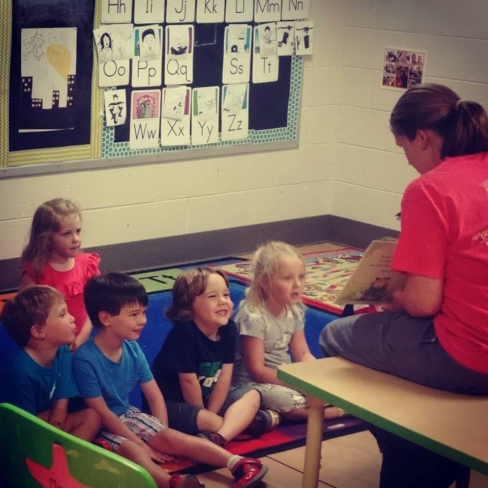 Adult reading to a group of children in a classroom