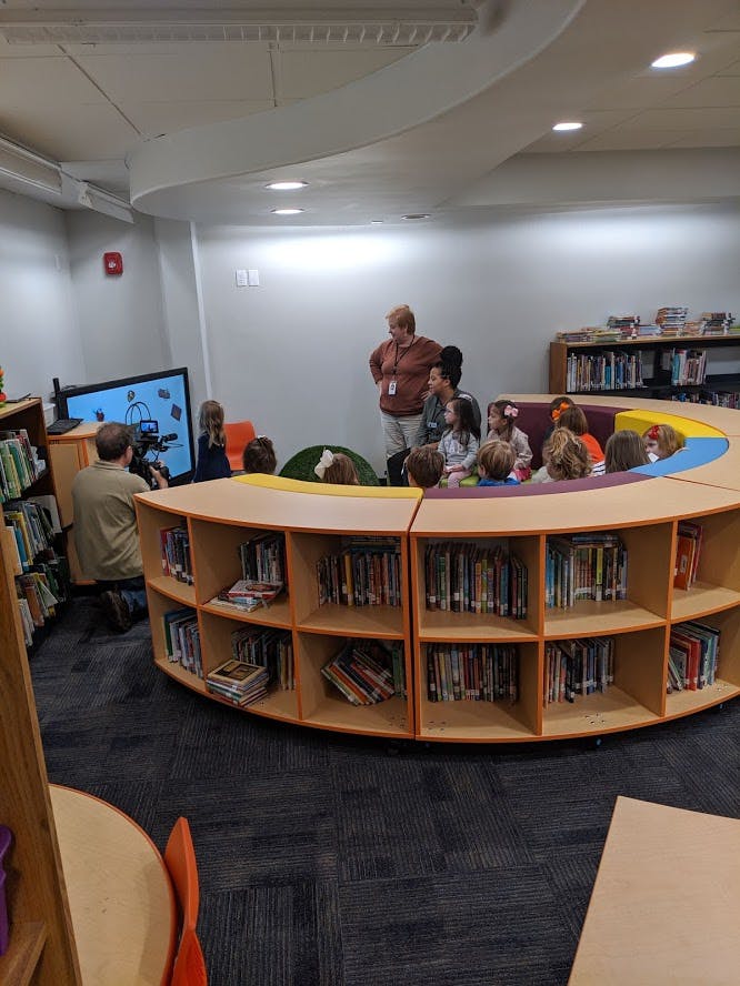 Adults and children gathered around a screen in a library