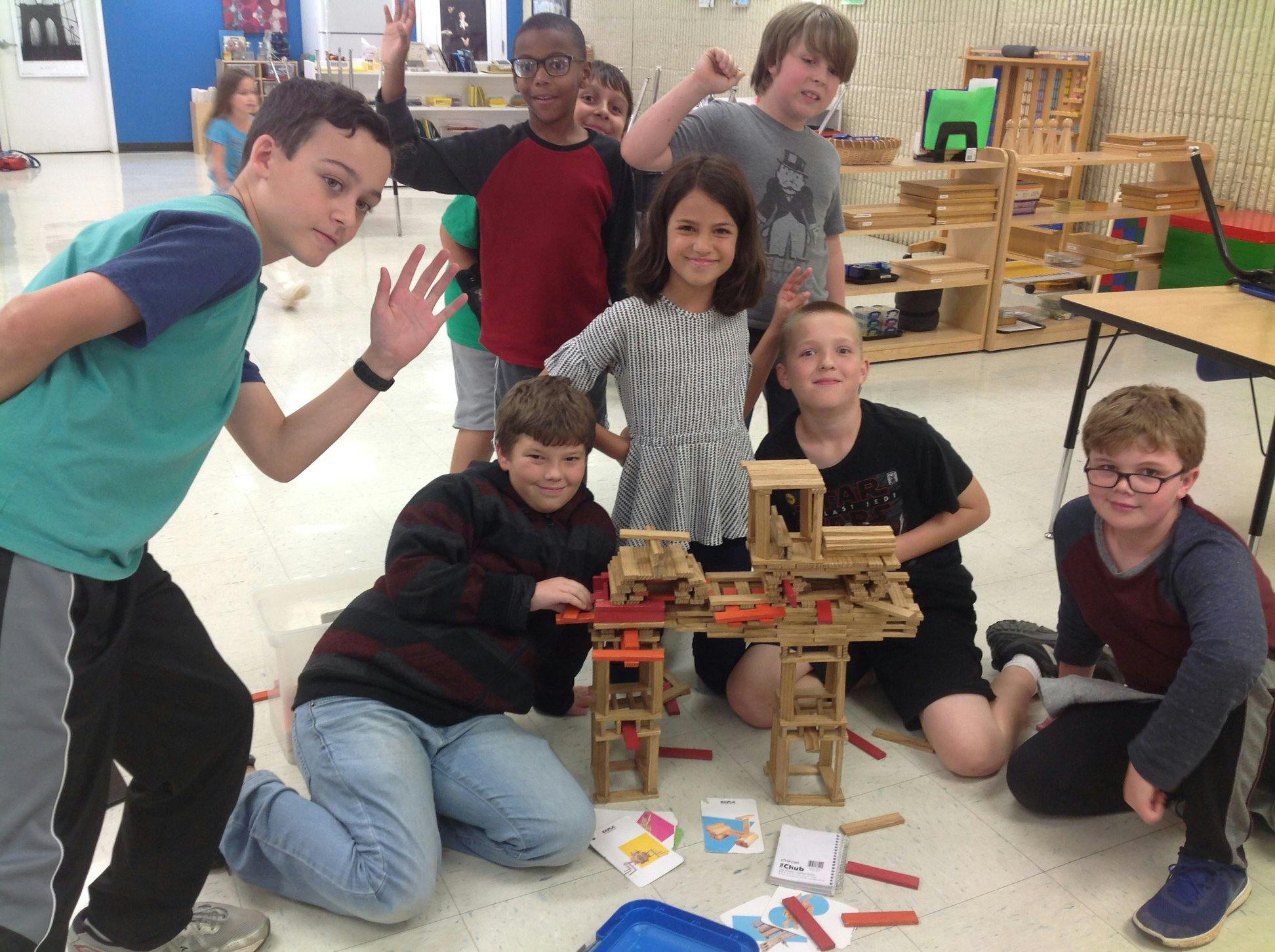 Group of children posing around a wooden block structure