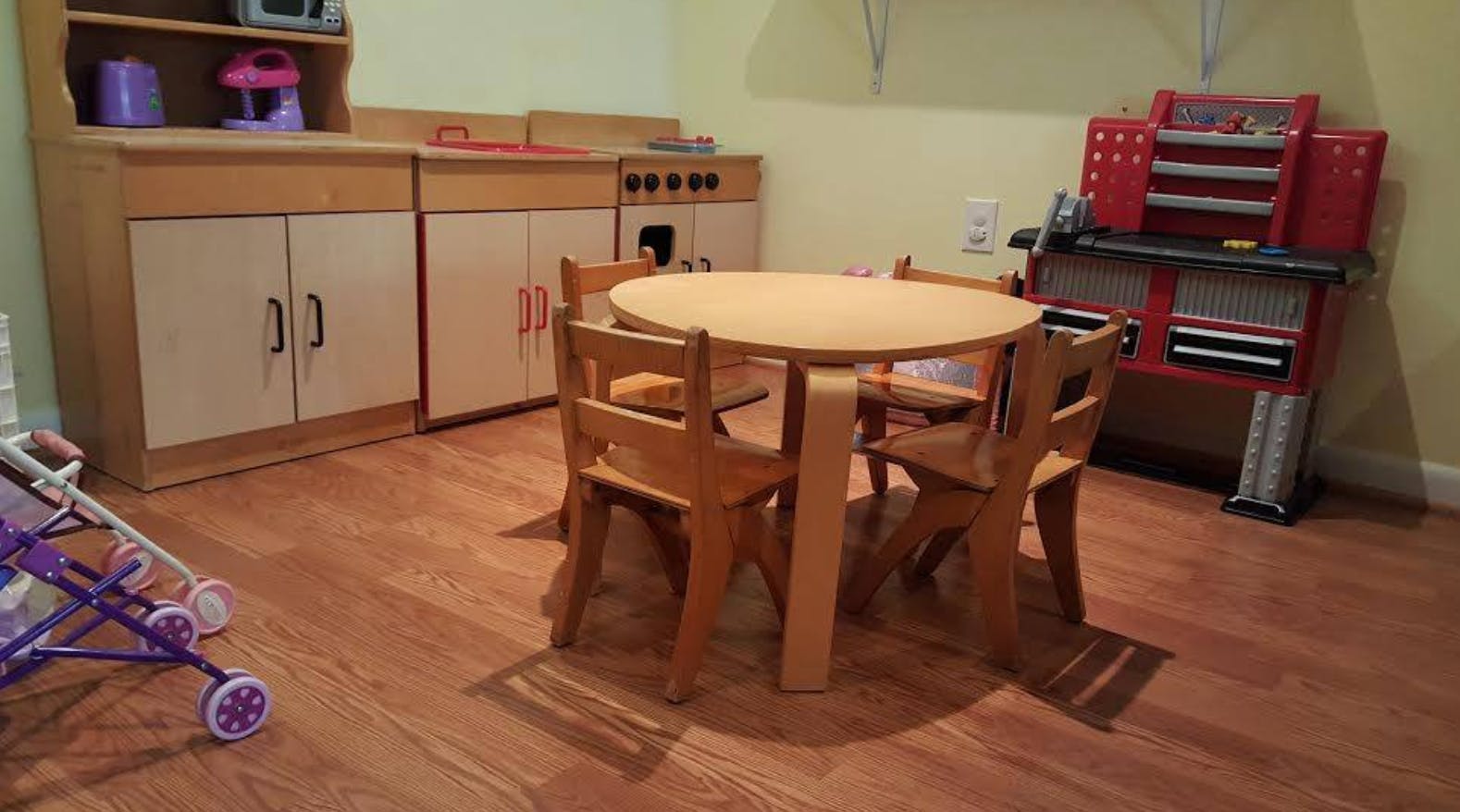 Playroom with toy kitchen, table and chairs, and toy workbench