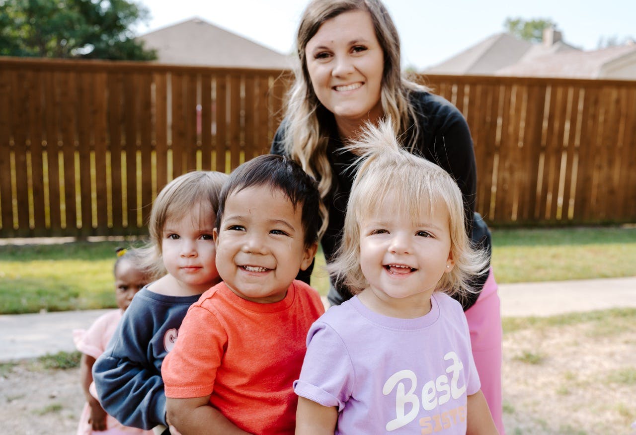 Adult and multiple children smiling outdoors