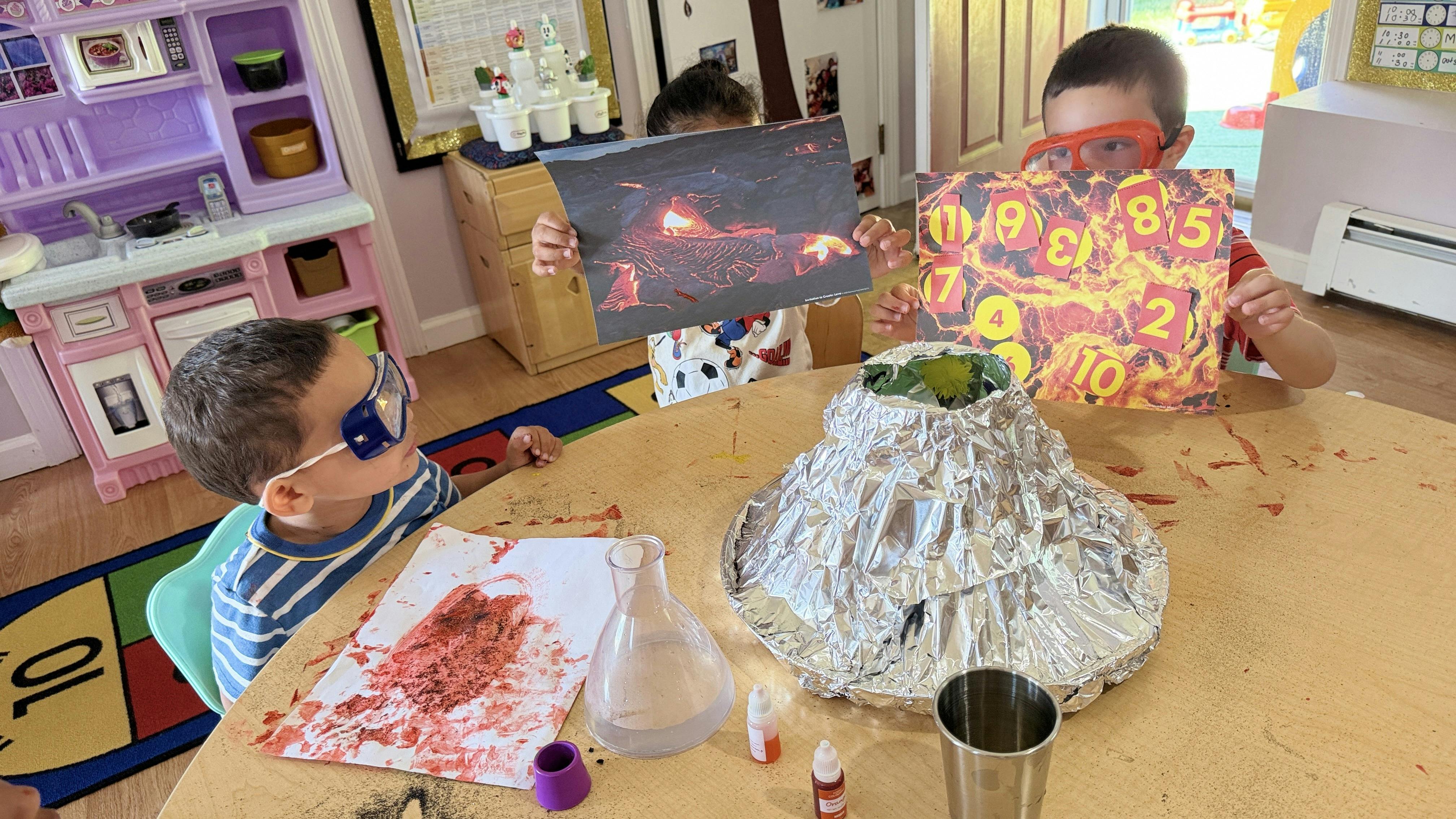 Children wearing safety goggles during a volcano science activity at a table