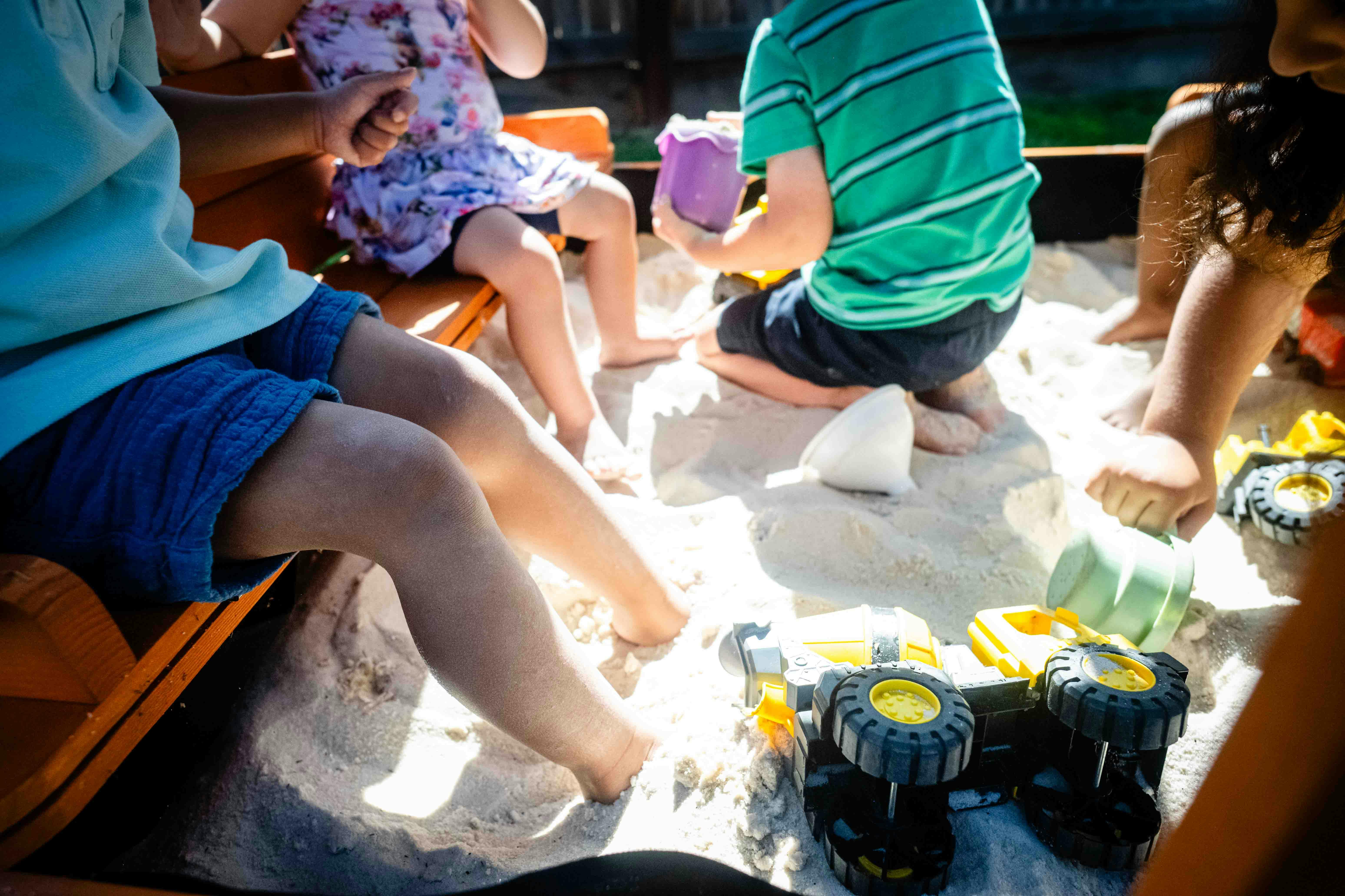 Children playing in a sandbox with toys