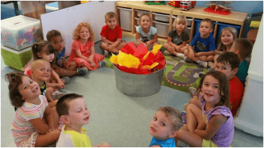 Children sitting in a circle around a craft fire