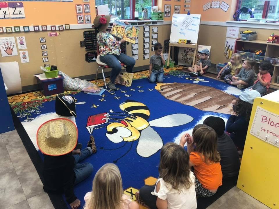 Person reading a book to a group of children in a classroom
