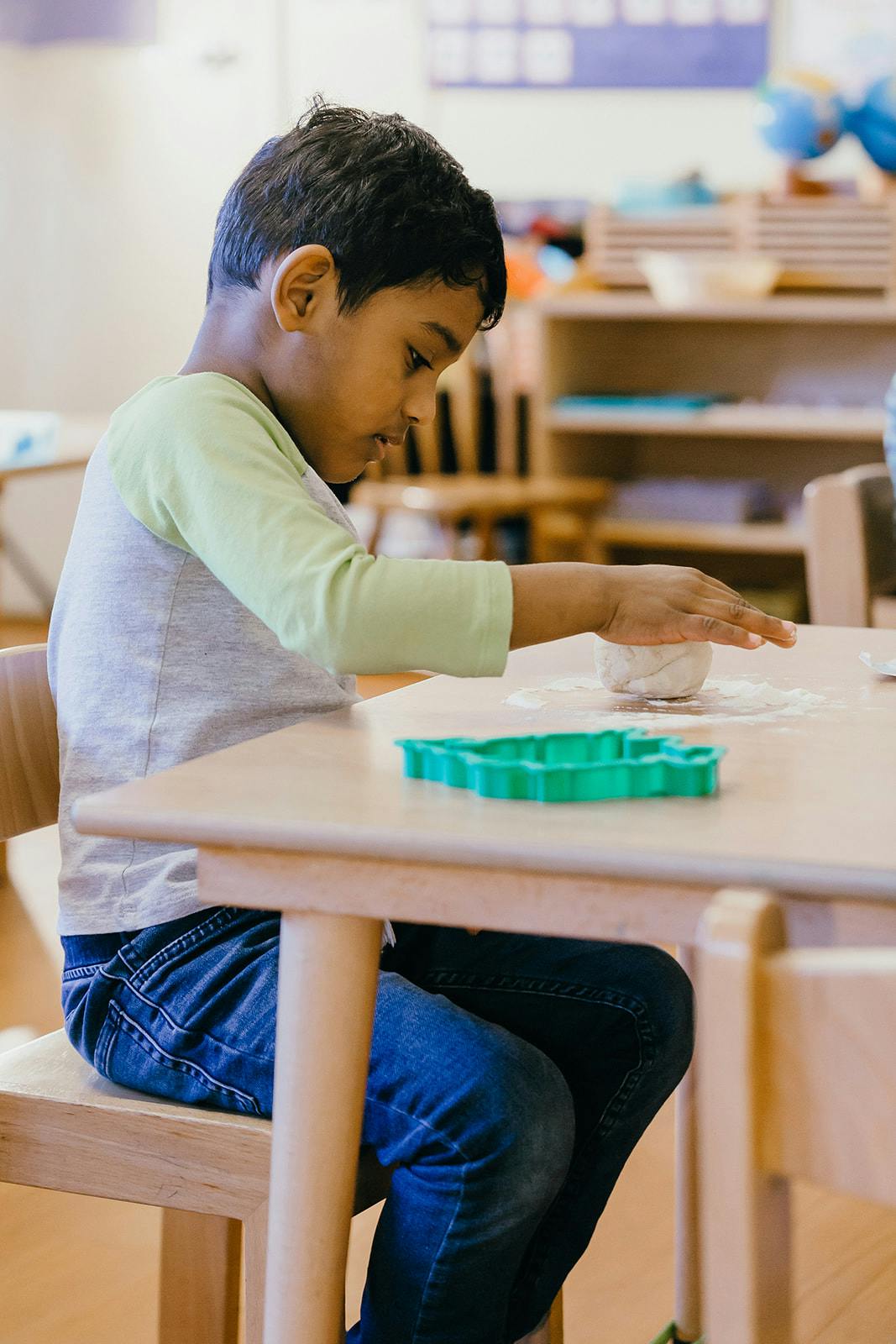Child at a table with a cookie cutter and dough