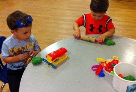 Two children playing with modeling clay at a table
