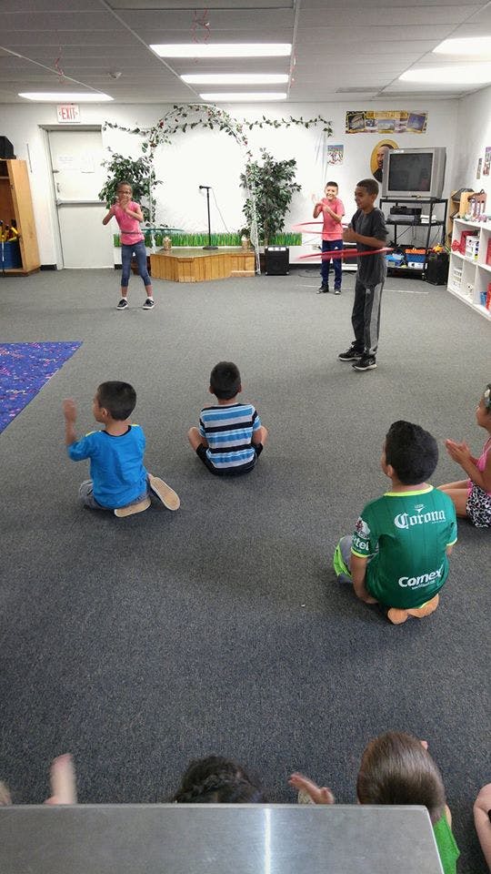 Children playing with hula hoops while other children sit on the floor watching