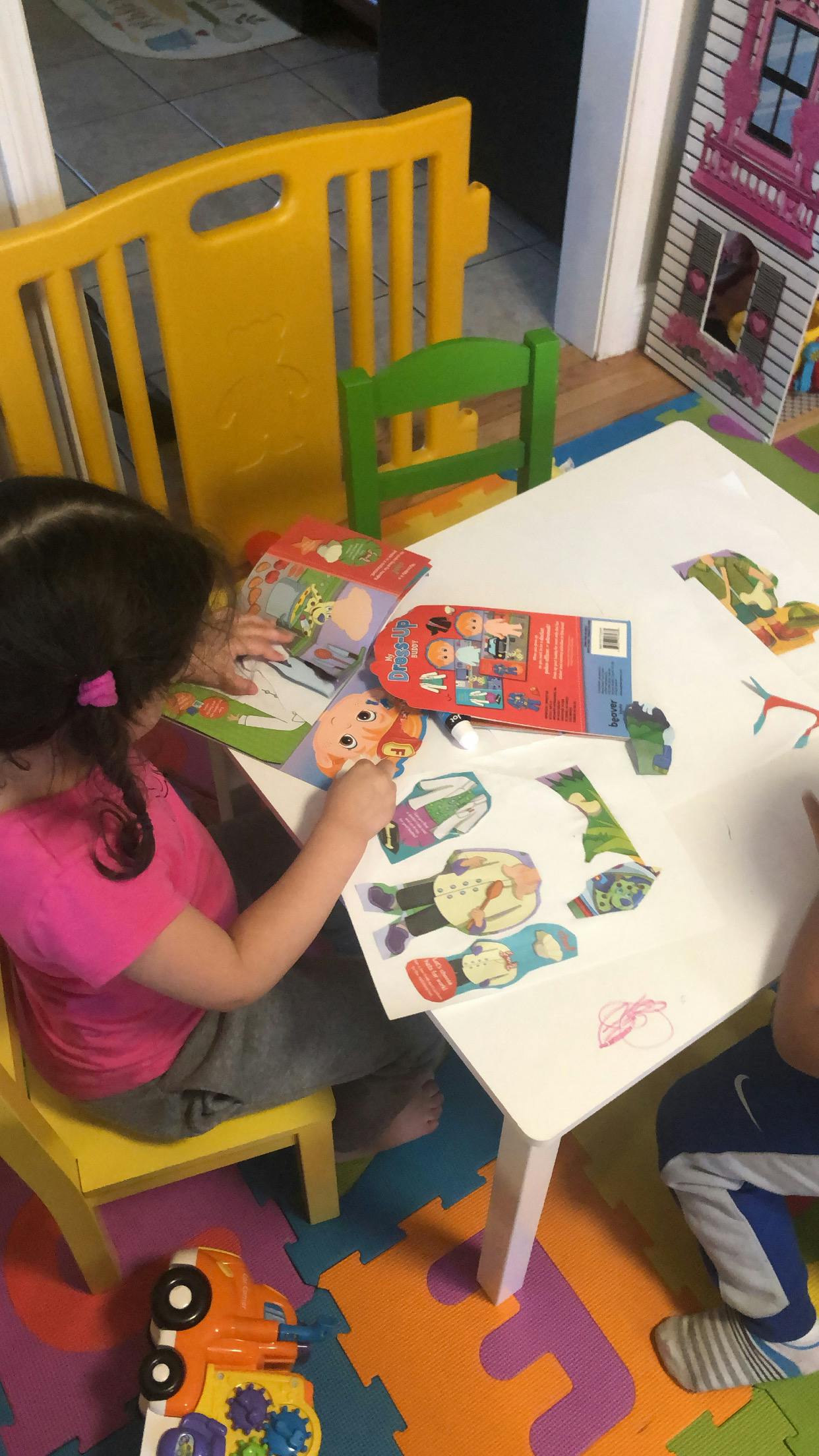 Child playing with paper cutouts at a table