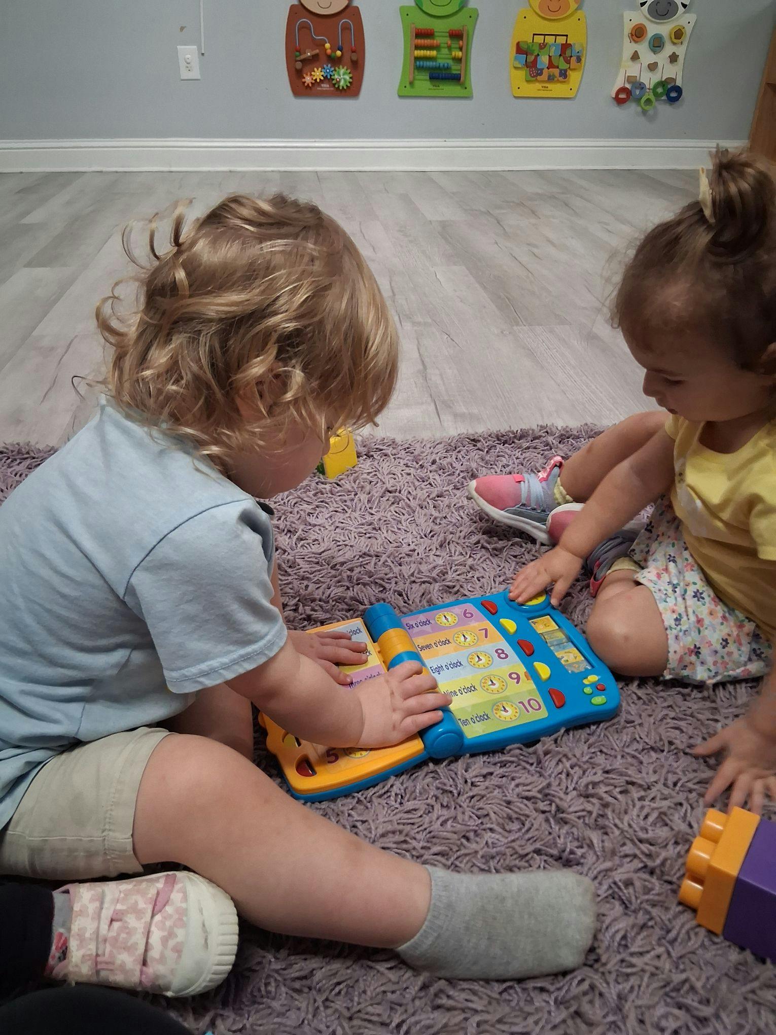 Two children sitting on a carpet playing with an educational toy