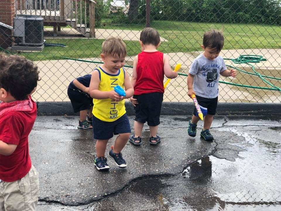 Children playing with water toys on wet pavement