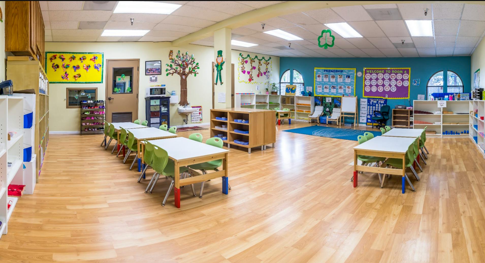 Empty preschool classroom with small tables and chairs