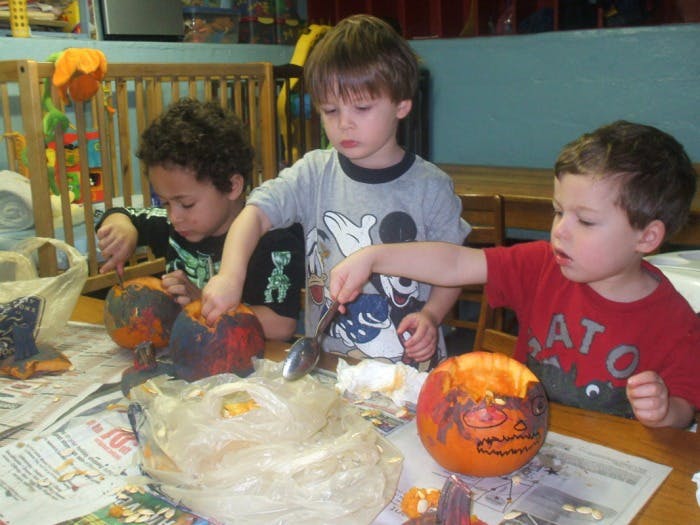 Three children carving pumpkins at a table