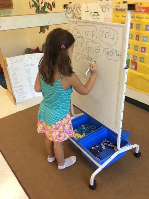 Child writing on a whiteboard in a classroom
