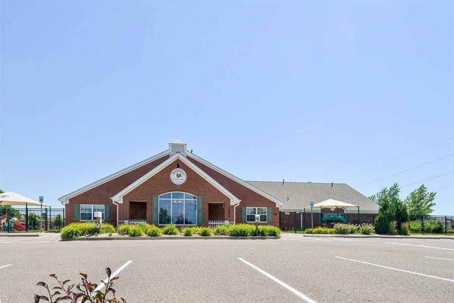 Brick building with a large arched window and a parking lot in front