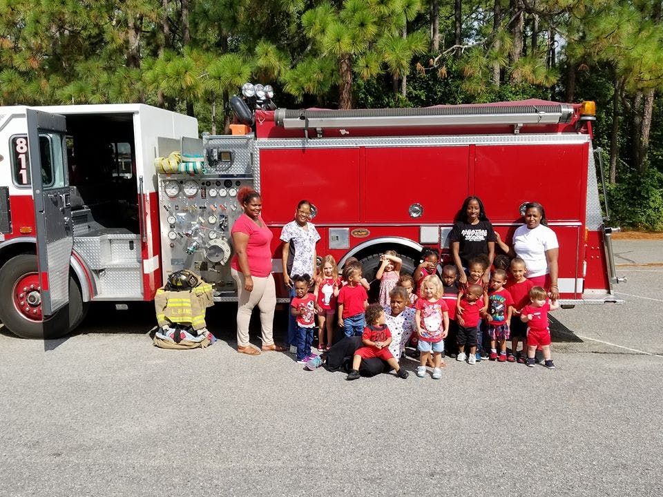Adults and children standing in front of a fire truck