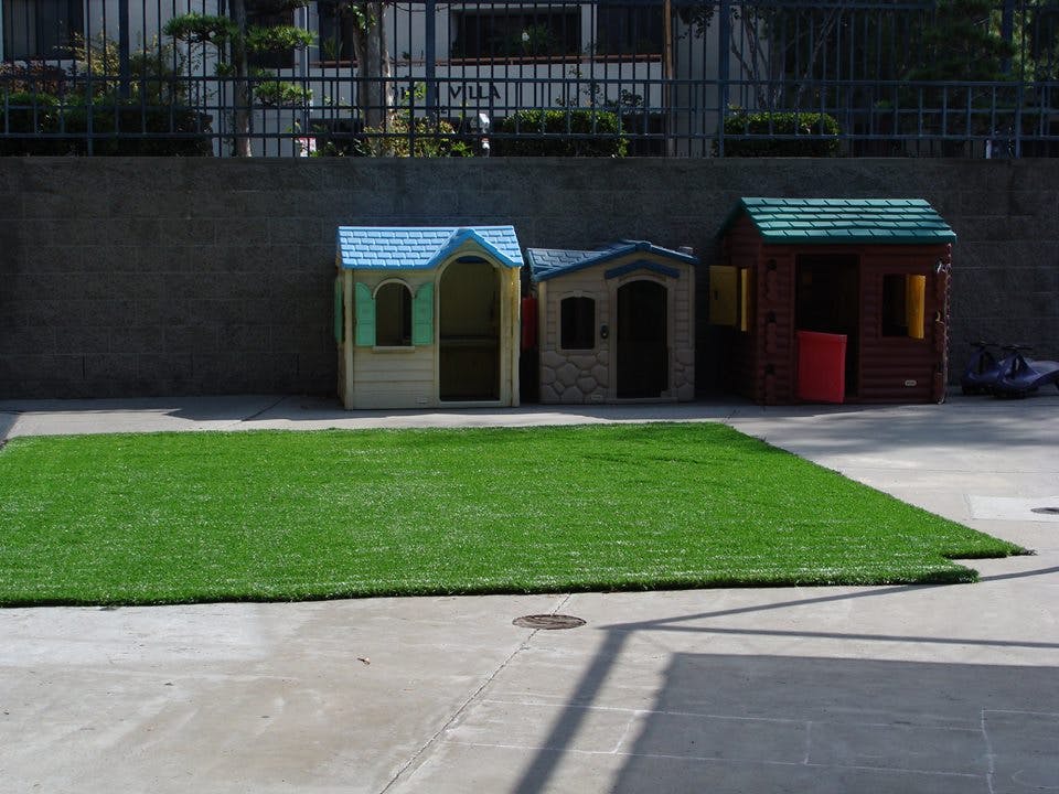 Artificial turf on concrete with three small playhouses