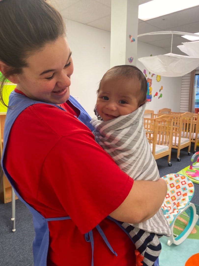 Person holding a swaddled infant in a classroom