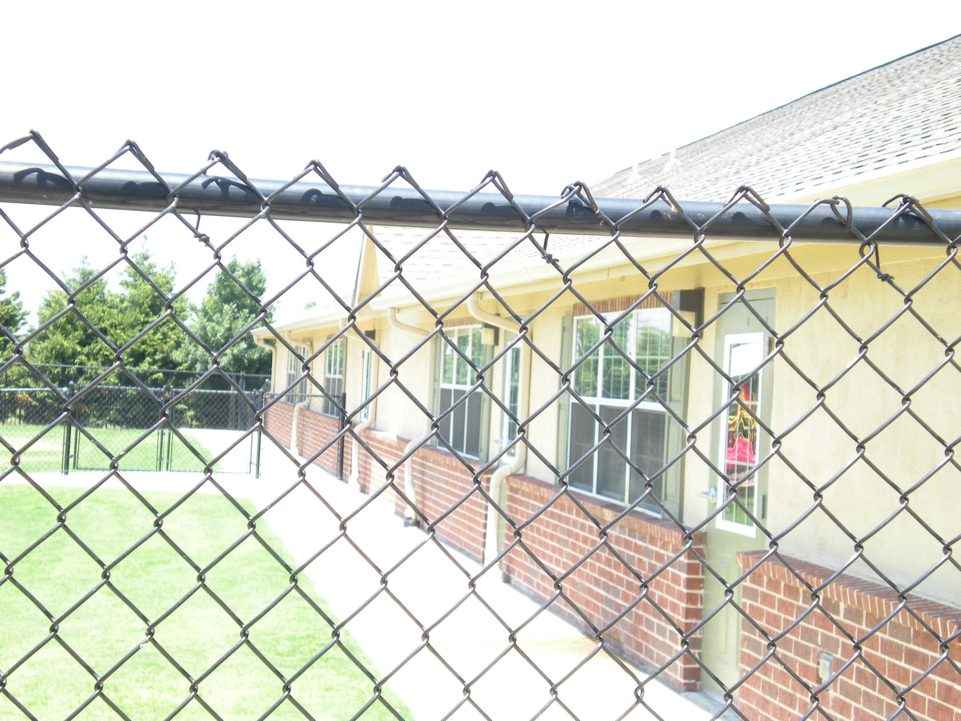 Chain link fence in front of a building with windows and brick siding