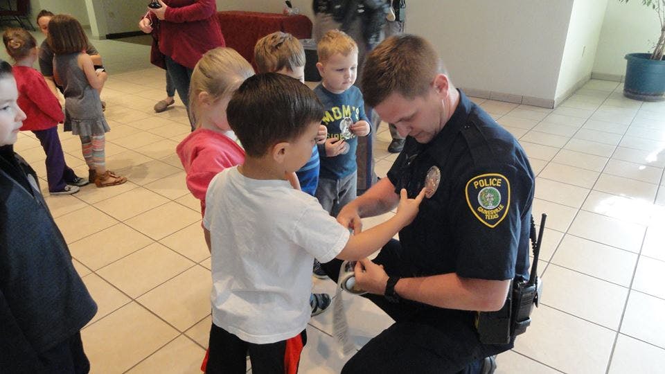 Police officer kneeling and interacting with children