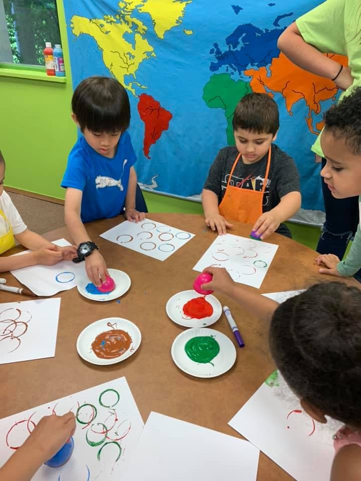 Children doing art with paint and paper at a table