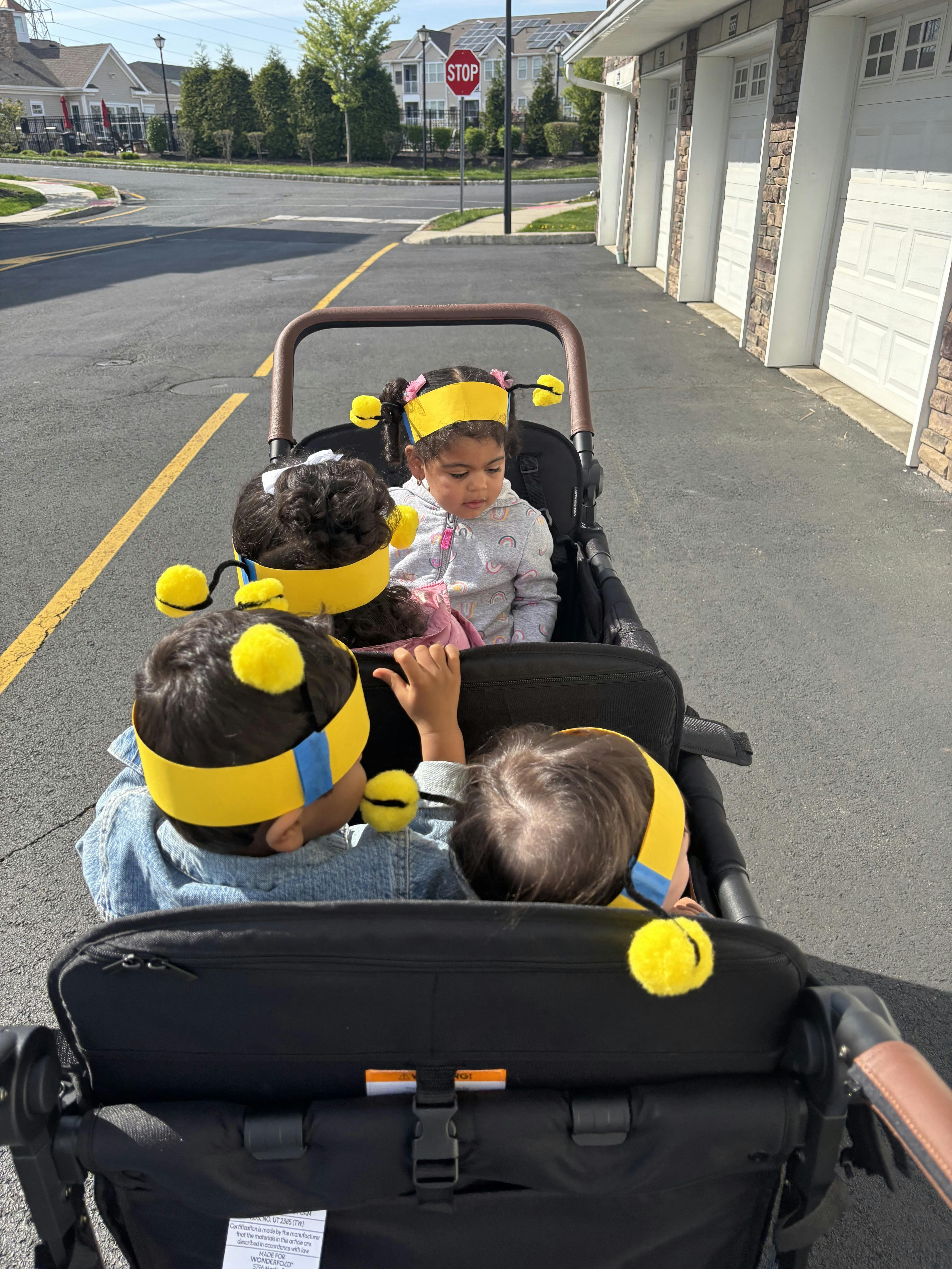 Three children in a stroller wearing yellow headbands