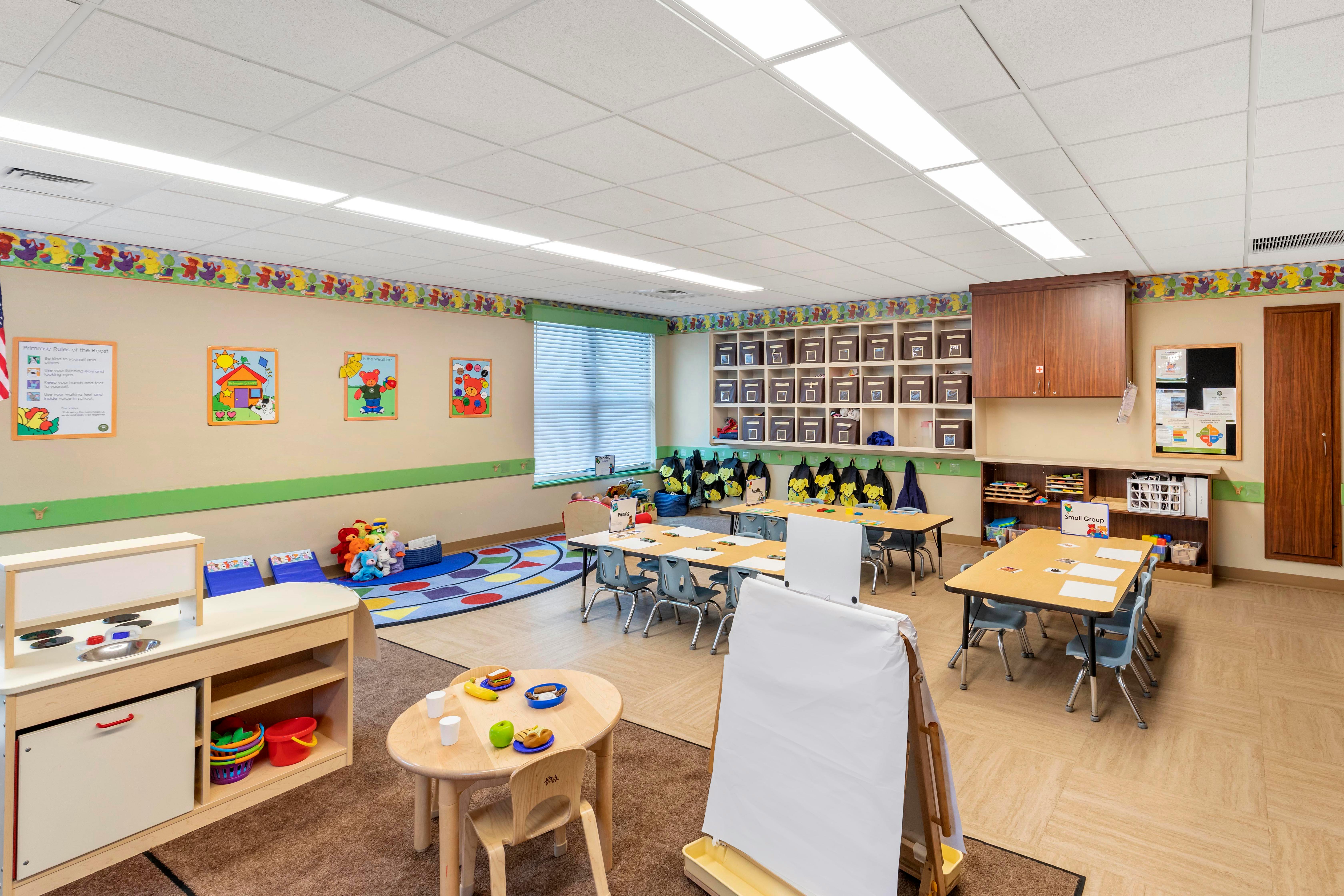 An empty early childhood classroom with small tables and chairs