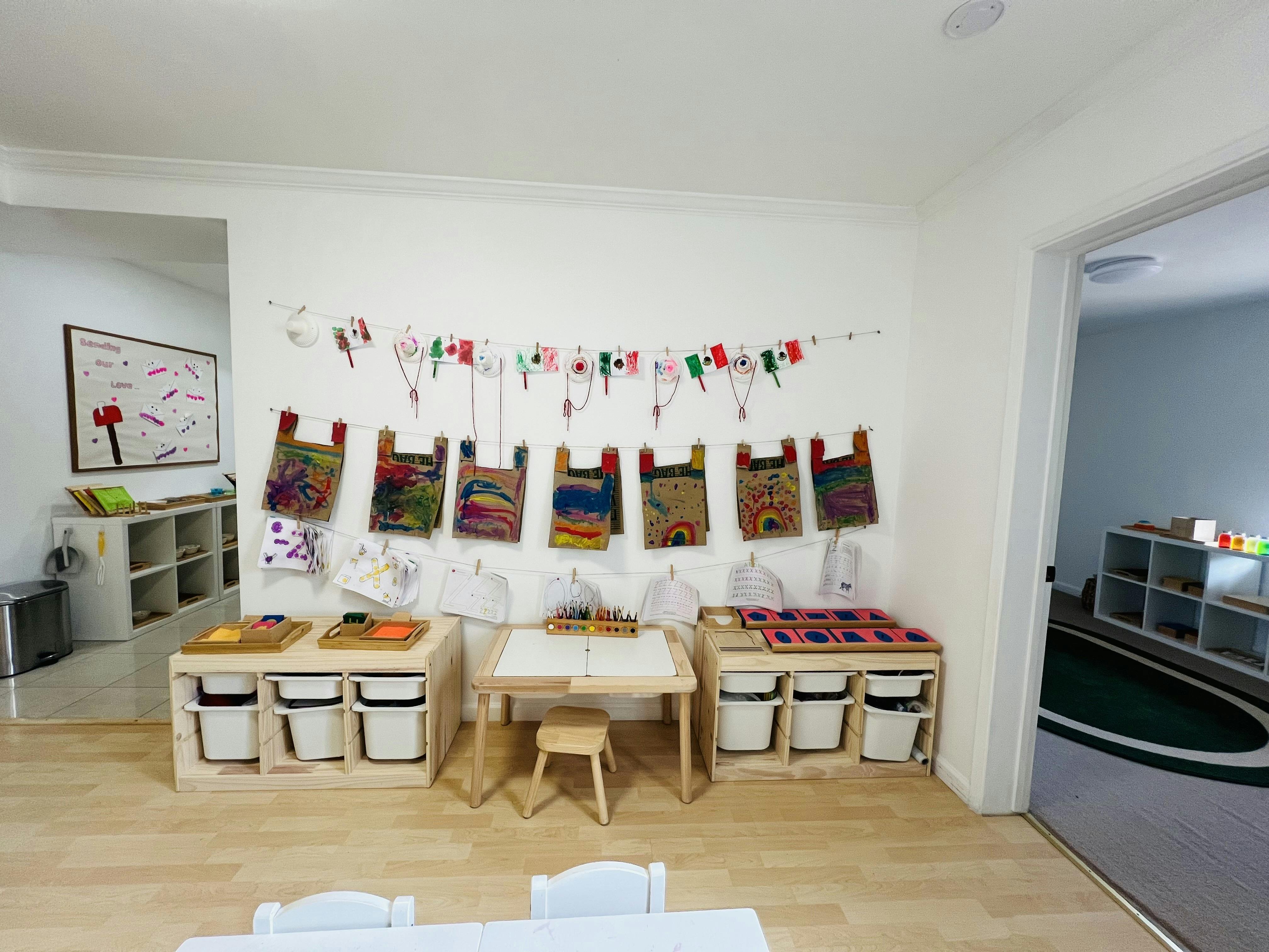Classroom wall displaying children's artwork hanging on clotheslines