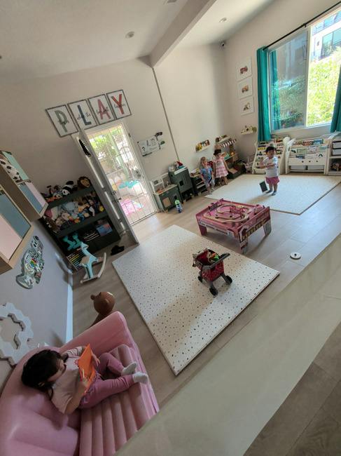 Children playing in a brightly lit playroom with toys and activity mats
