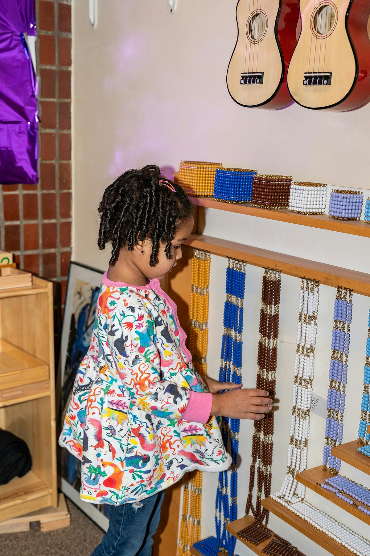 Child looking at colorful beaded strings and blocks on a shelf