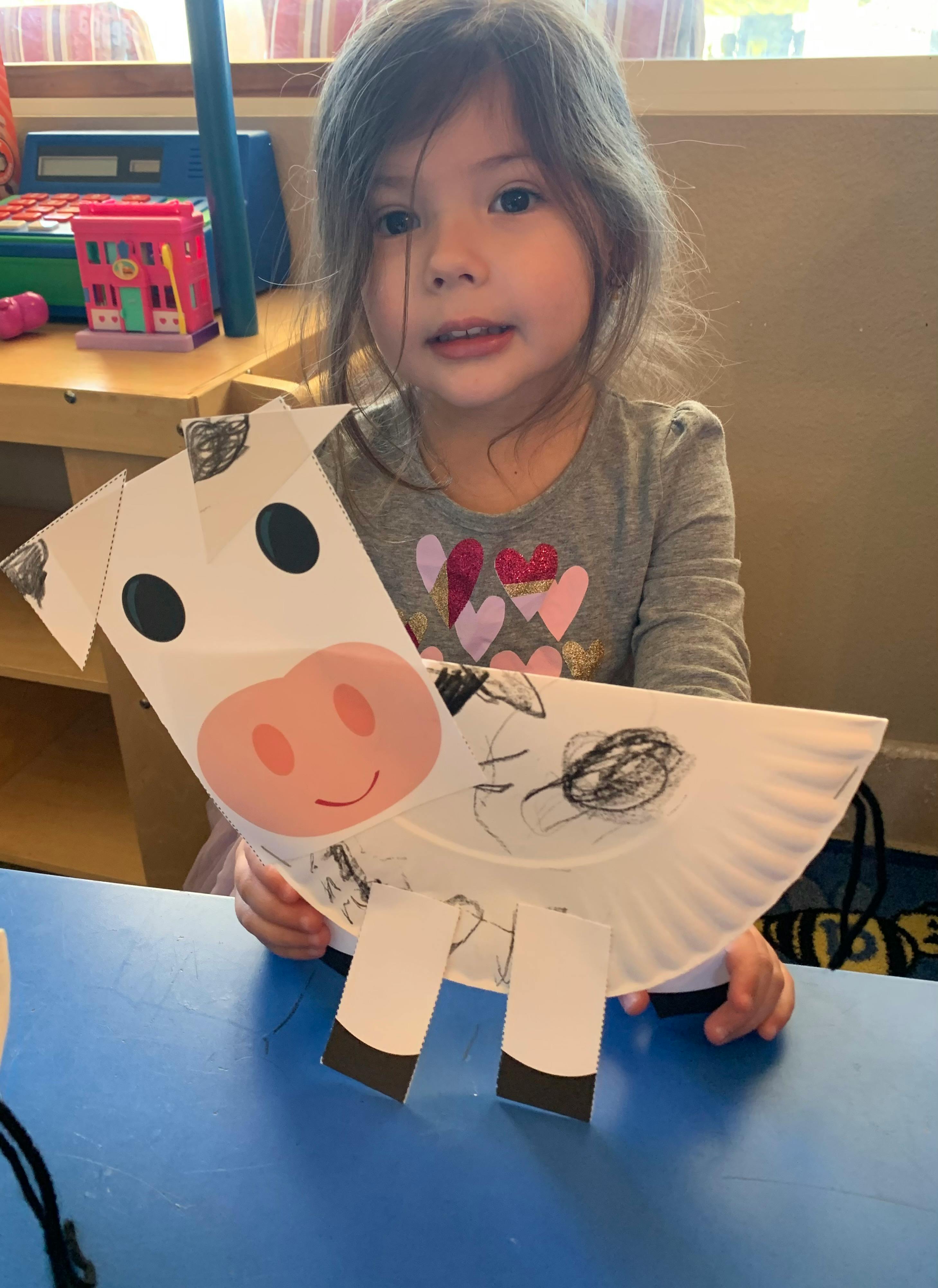 Child holding a paper plate cow craft