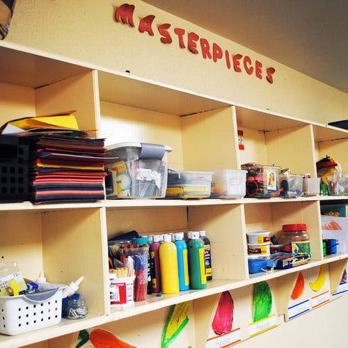 Shelves with art supplies and the word "MASTERPIECES" on the wall