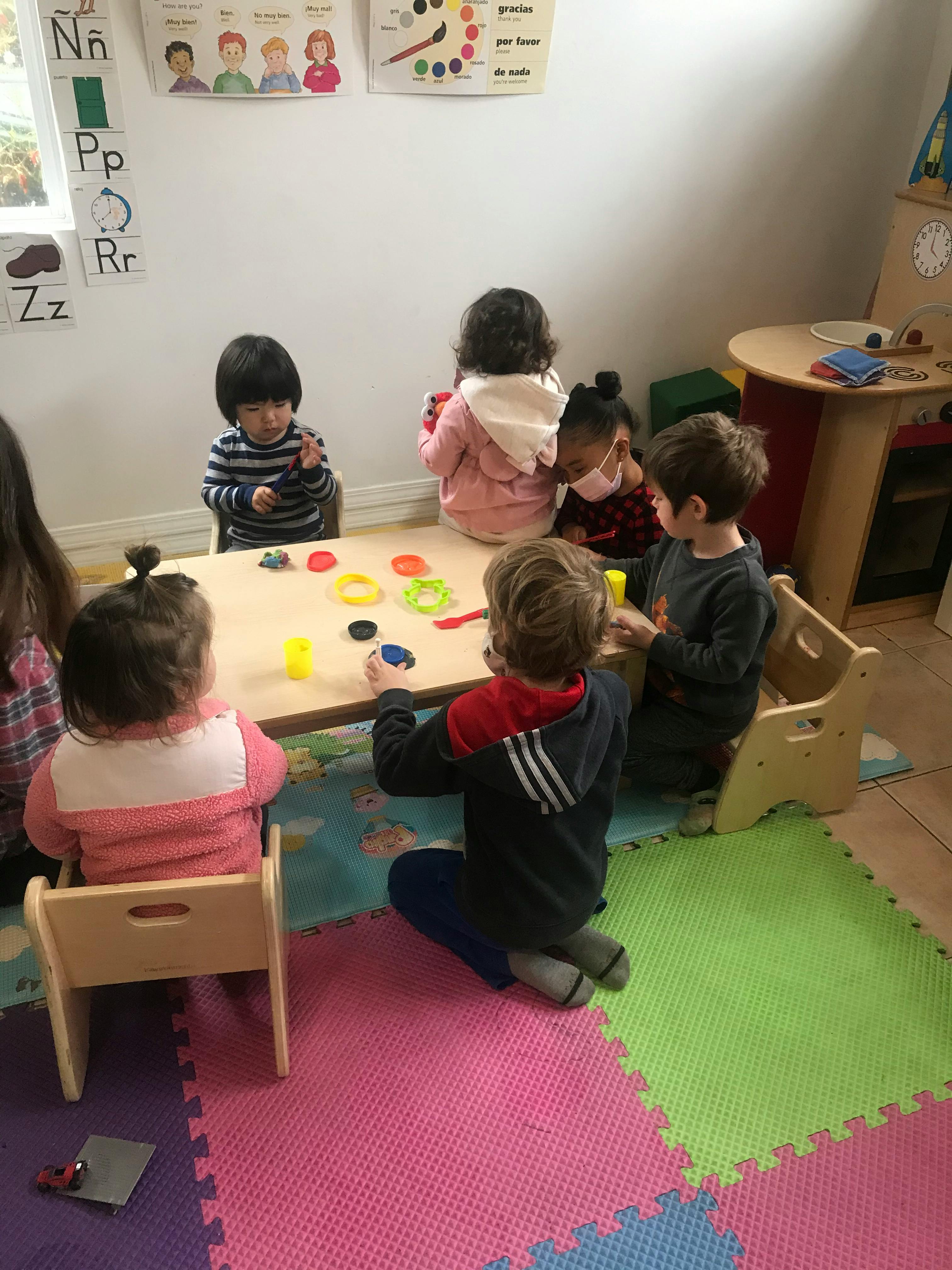 Children playing with colorful objects at a table in a classroom