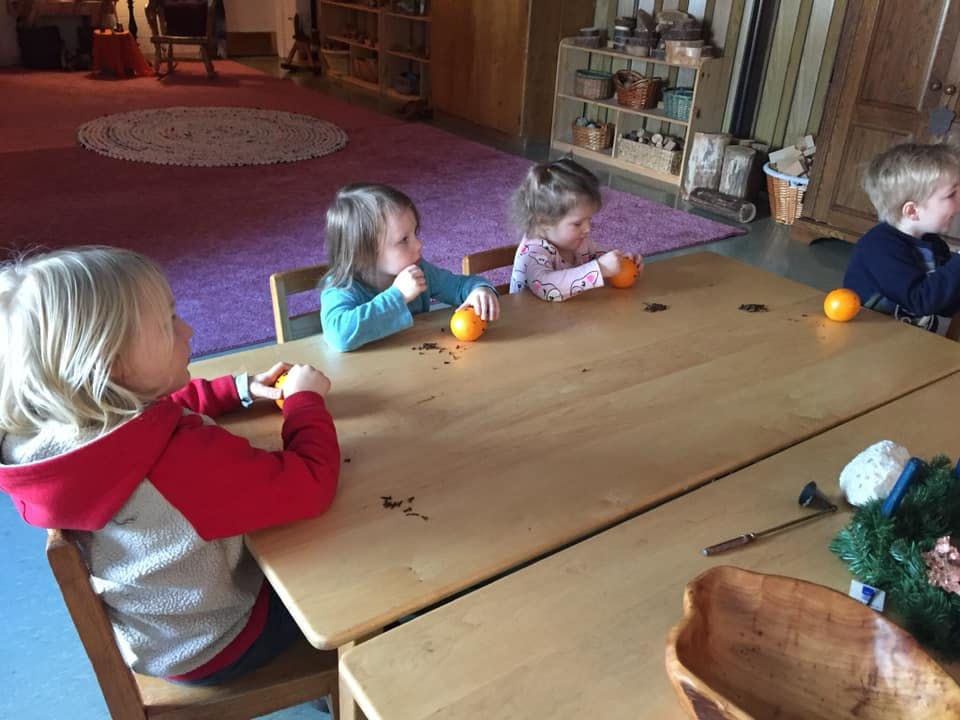 Children sitting at a table with oranges