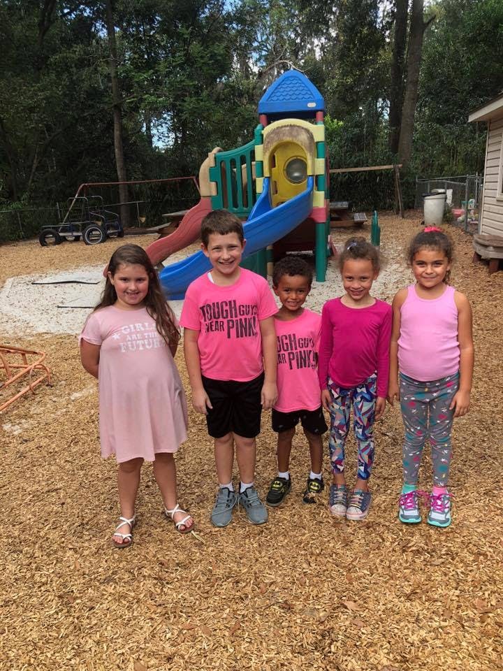 Five children standing in front of a playground structure