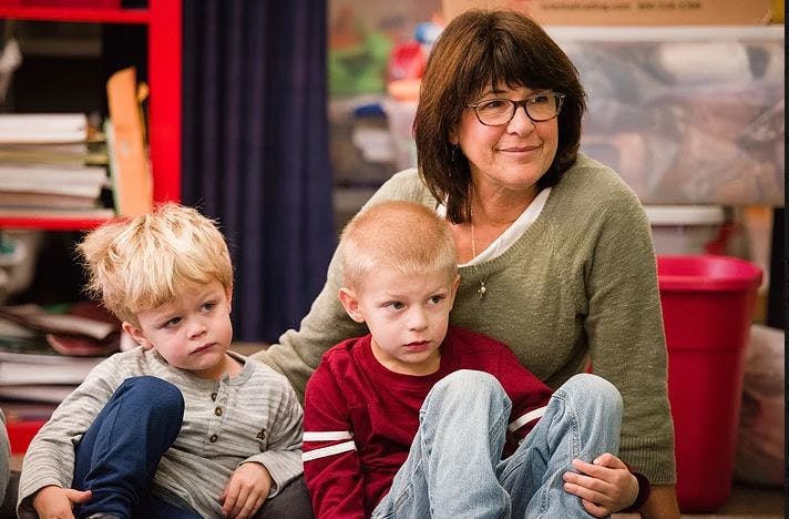 Adult person with two children in a classroom