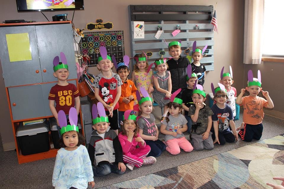 Group of children wearing bunny ear headbands in a classroom