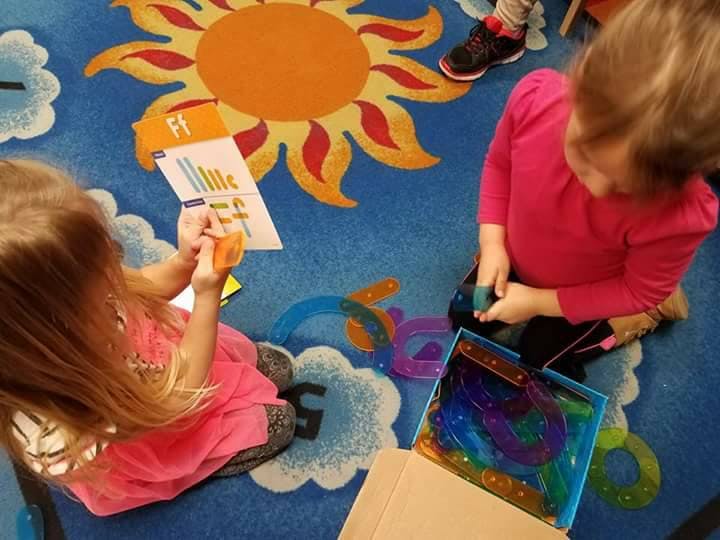 Two children playing with toys on a sun-patterned rug