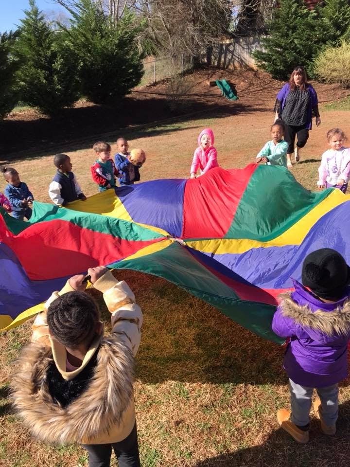 Children playing with a colorful parachute outdoors
