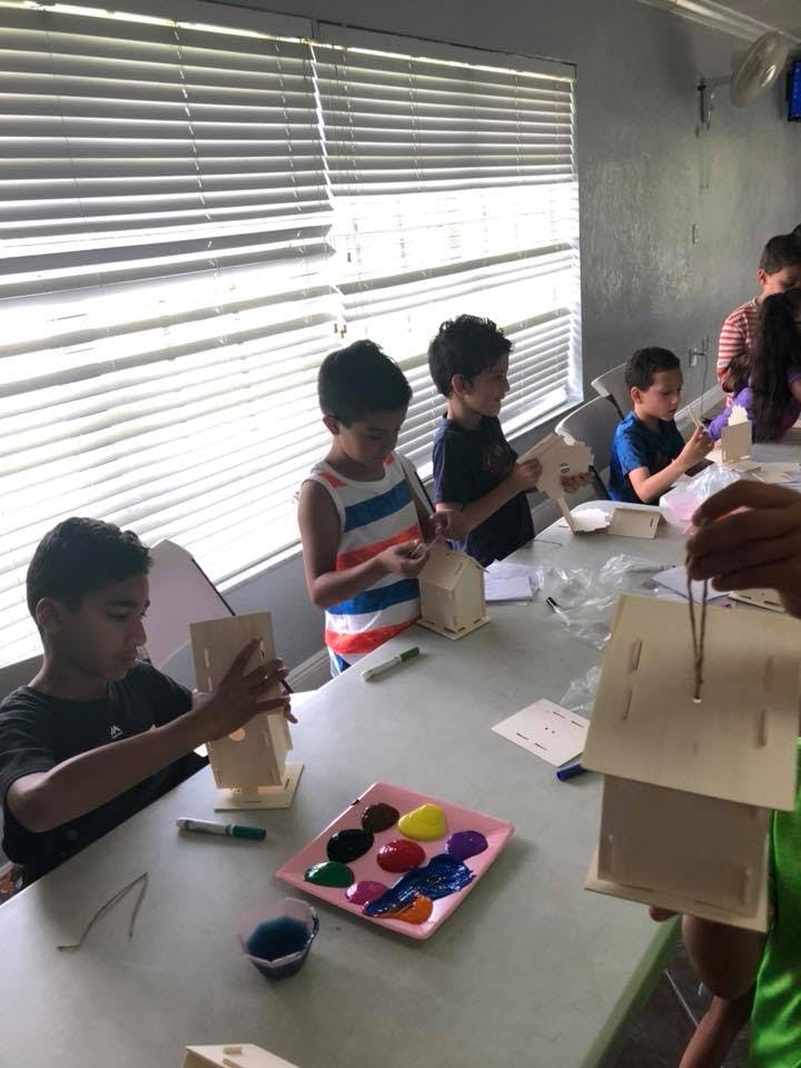 Children at a table assembling small wooden birdhouses