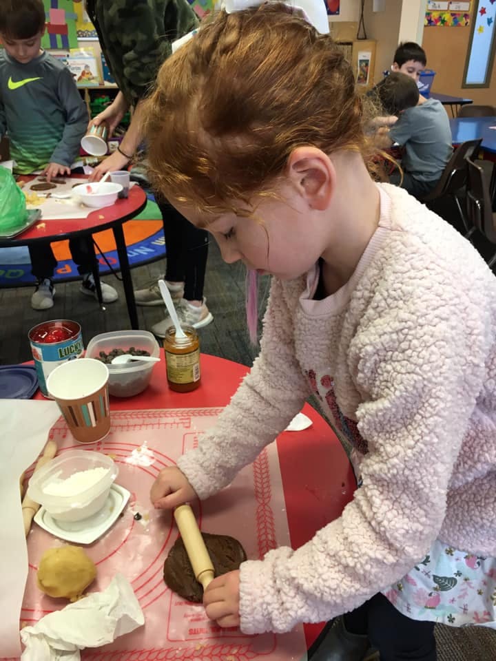 Child rolling out dough with a small rolling pin