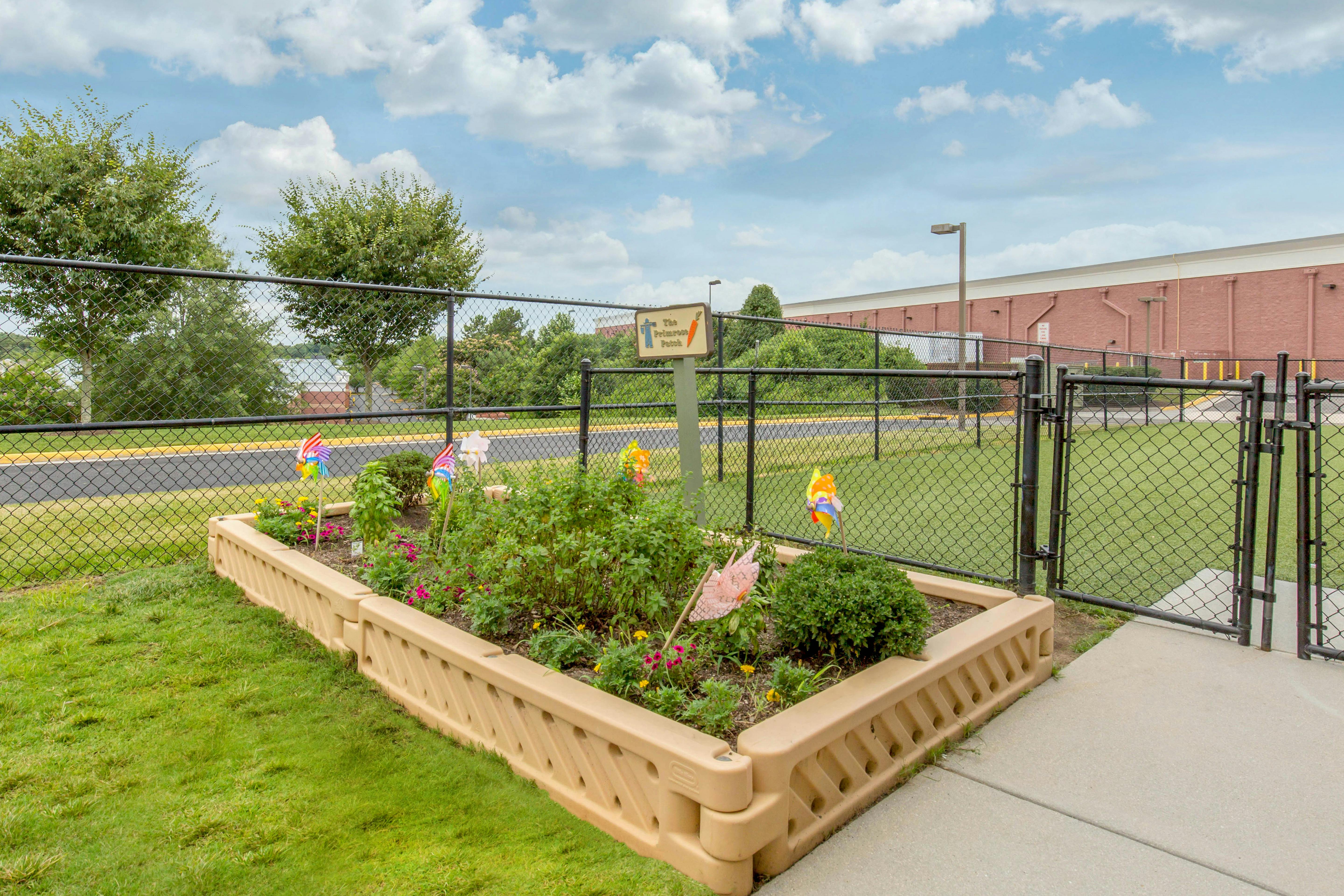An outdoor raised garden bed with various plants and small colorful pinwheels