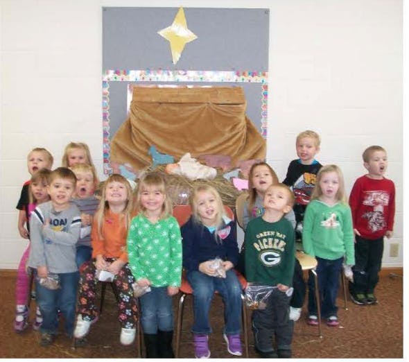 Group of children posing in front of a nativity scene