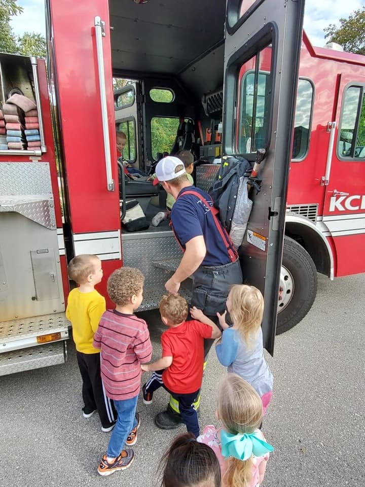 Person in uniform showing children the inside of a fire truck