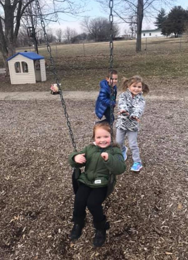 Three children playing on a swing set at a playground