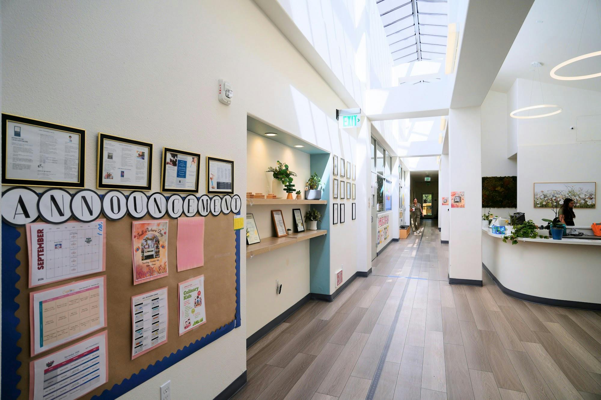 A hallway with an announcement board on the left and a front desk on the right