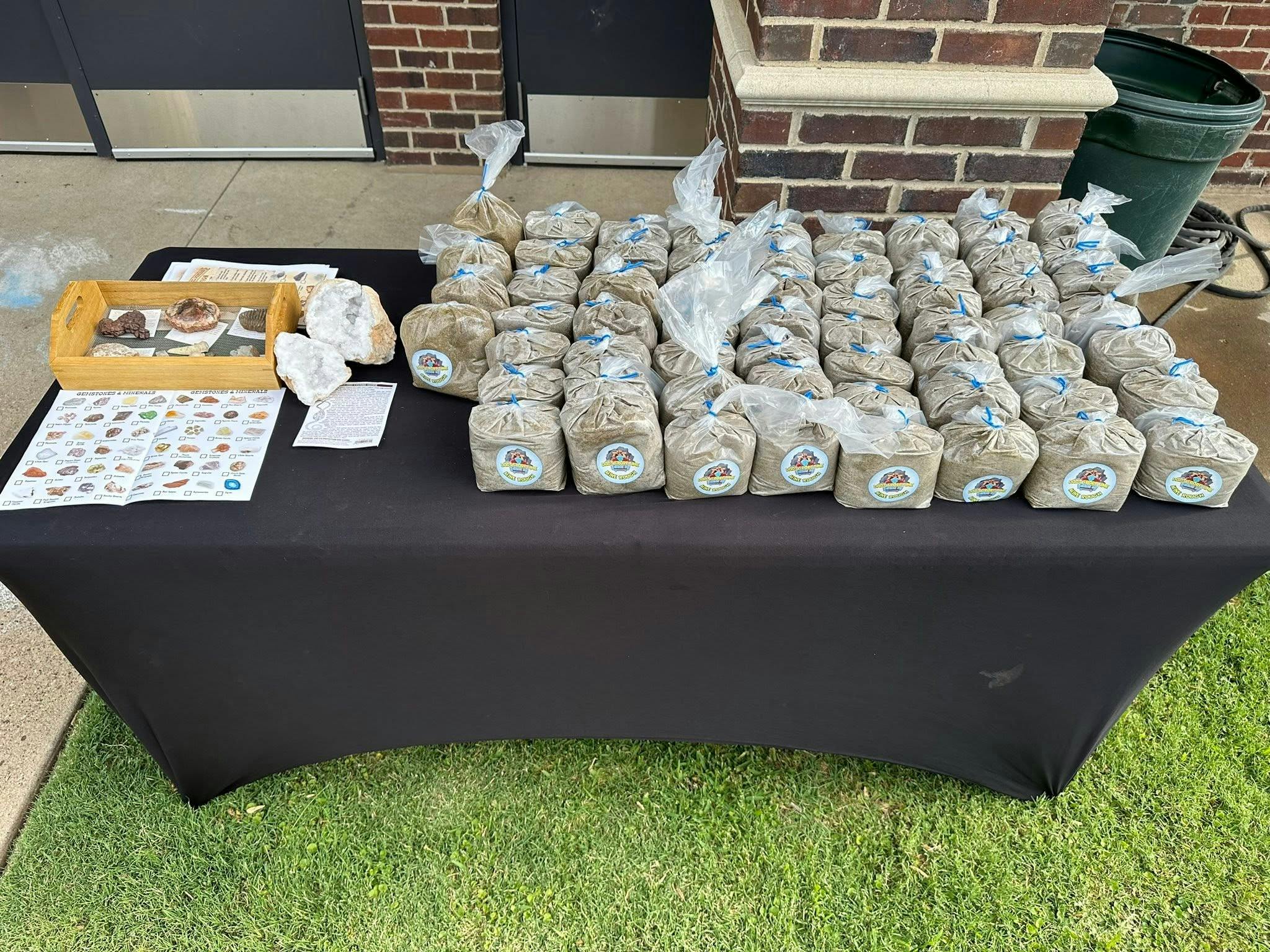 Table covered with bags of dirt and mineral specimen trays