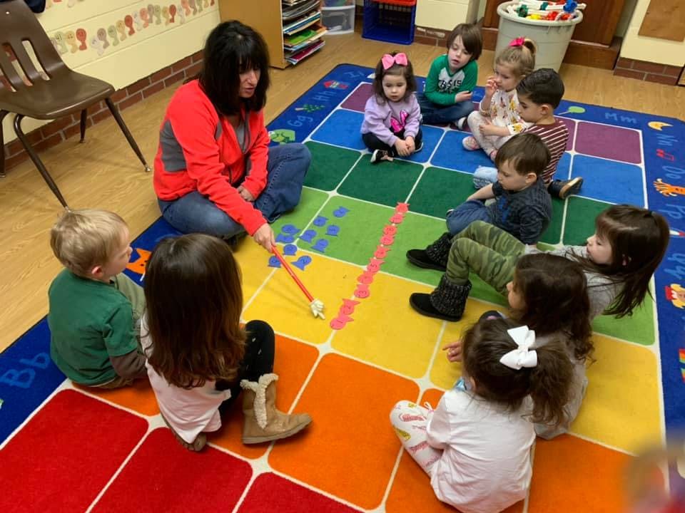 Person and children sitting on a colorful rug